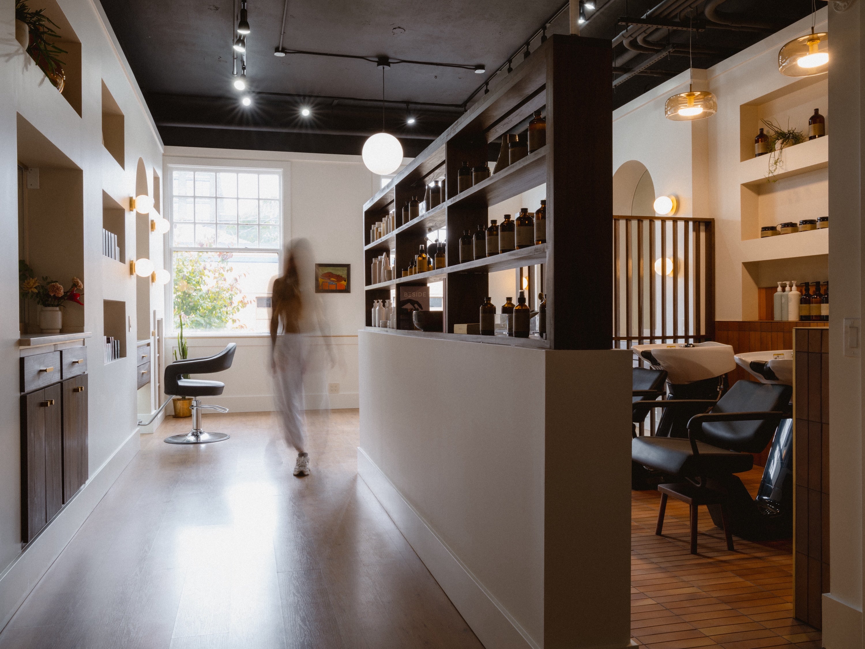 Modern interior design with shelves, chairs, and a person walking through a bright room.