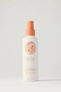 White spray bottle with orange nozzle of ROZ thickening spray on a light gray background