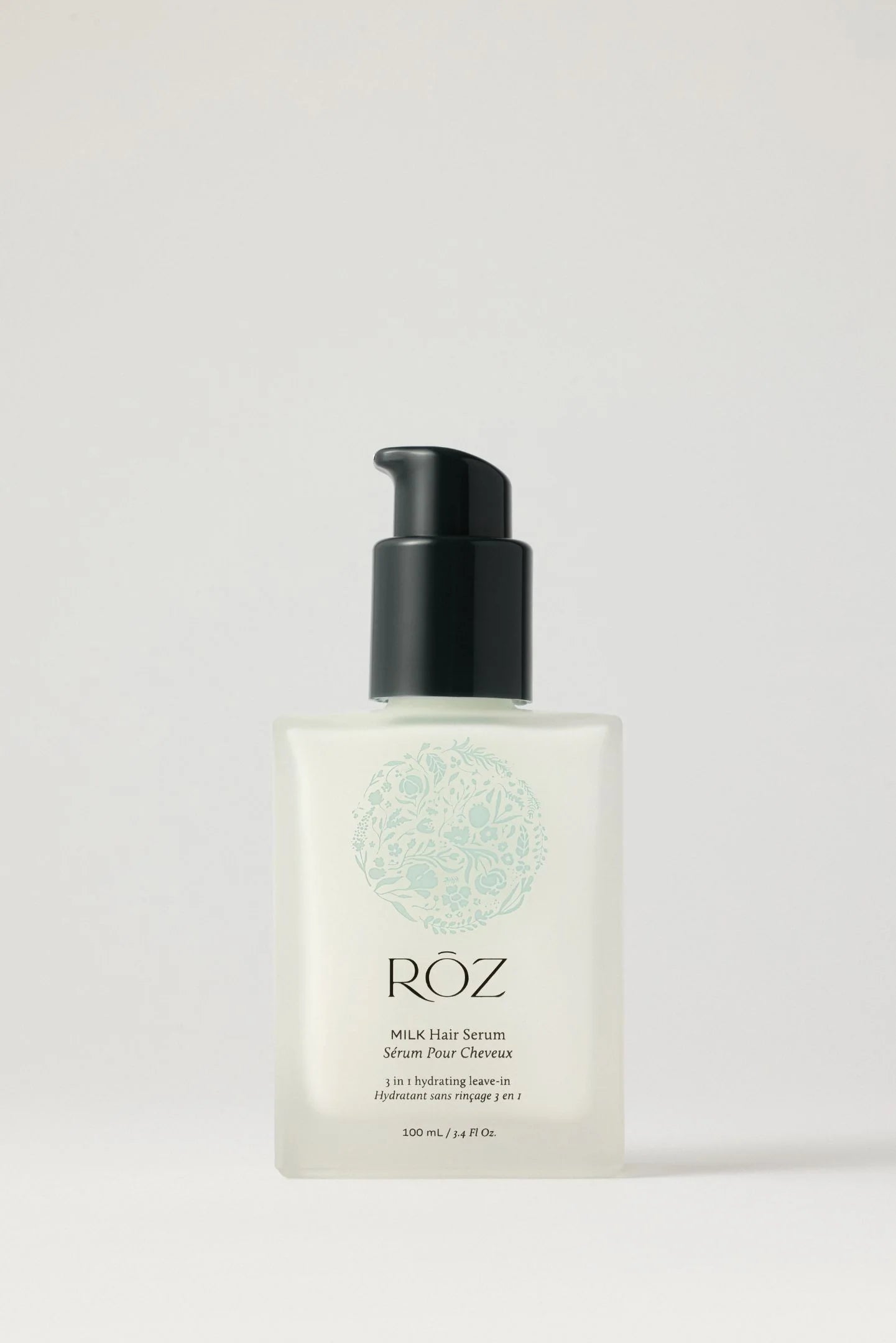 White bottle of ROZ milk hair serum with black top on white background