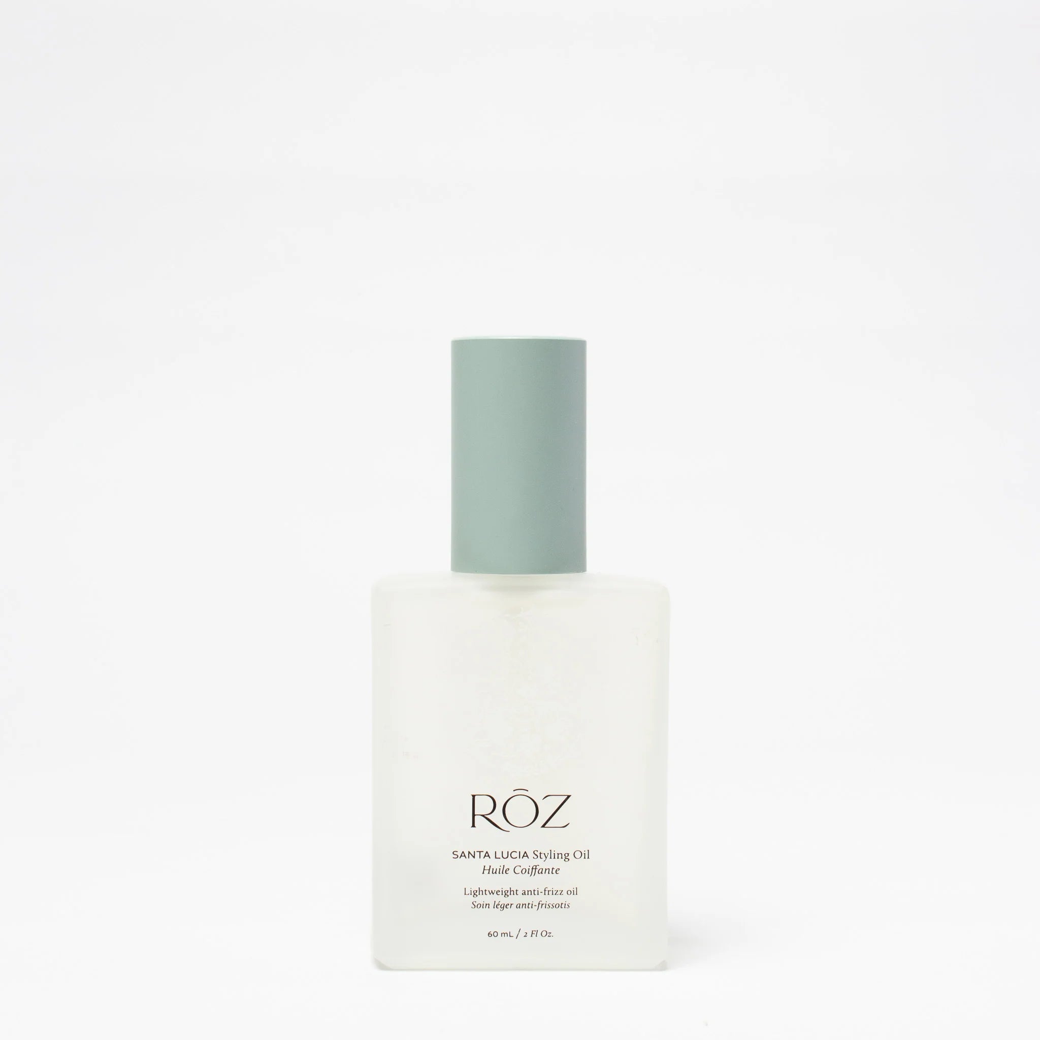 Clear bottle of ROZ Santa Lucia styling oil with green top on white background